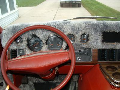 1978 Ford E250 - Van interior with furry dash cover and red steering wheel. Another vehicle is visible outside.