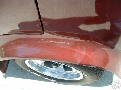 1978 Ford E250 - Close-up of a maroon van's rear wheel well, revealing scuff marks on the metallic paint.