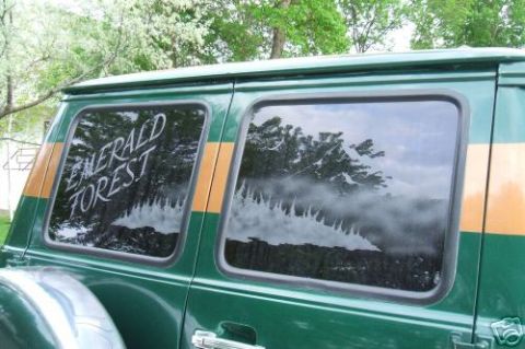 1978 Ford E250 - Rear side of a green van with an orange stripe and writing on the window.
