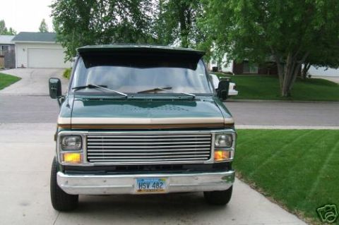 1978 Ford E250 - Front view of a green van with a prominent chrome grille and tan trim, parked on a concrete driveway.