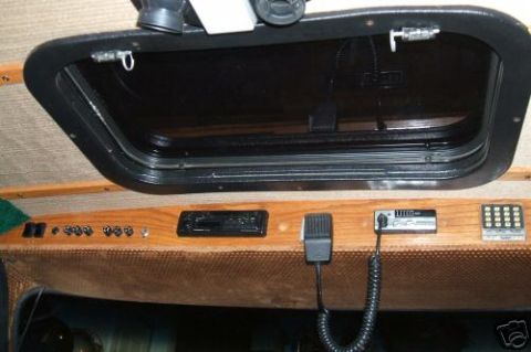1978 Ford E250 - Dashboard area of a vehicle showing a radio, microphone, and control panel with a tinted window above.
