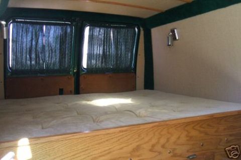 1978 Ford E250 - The inside of a van conversion shows a bed platform and curtains covering the rear windows.