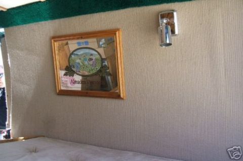 1978 Ford E250 - A framed mirror depicting a vineyard scene hangs on the wall of a van's interior, next to a light.
