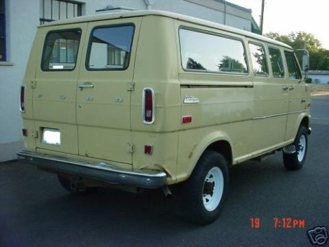 1978 Ford E250 - Three-quarter rear view of a tan/cream Ford Club Wagon van with barn-style rear doors, chrome rear bumper, vertical taillights and body-sid…