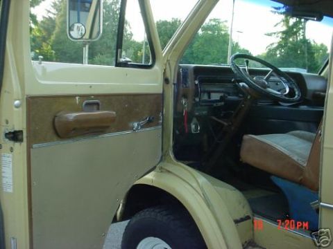 1978 Ford E250 - Cream-colored van photographed with the driver's door open, showing the flat door panel with a brown pull strap and chrome trim strip, the…