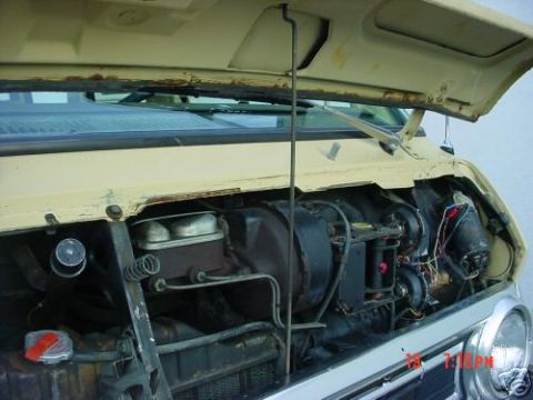 1978 Ford E250 - Open hood of a cream/tan van showing the engine bay from the driver's side, with the master cylinder and brake booster, a black round air c…
