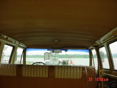 1978 Ford E250 - Interior of a van shot from the rear seats looking forward, showing a tan ribbed vinyl bench seat back, the ribbed headliner, dome light an…