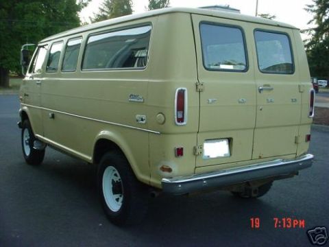 1978 Ford E250 - Rear three-quarter view from the driver's side of a tan/cream Ford Club Wagon window van with windowed rear barn doors, vertical taillights…