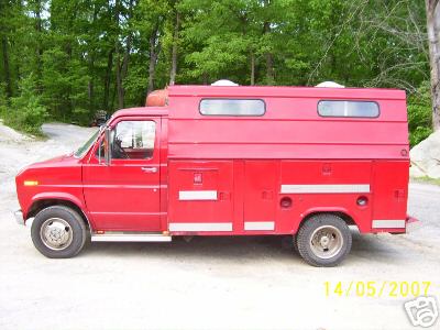 1978 Ford E250 - Side view of a red 1978 Ford E250 utility van with a custom camper shell and storage compartments.