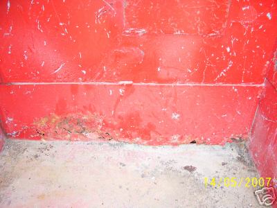 1978 Ford E250 - The interior of a red cargo area shows significant rust and damage at the base of the wall.