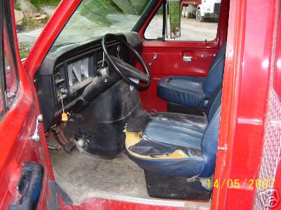 1978 Ford E250 - Interior view of a red van, showing the dashboard, steering wheel, and blue seats. The van appears to be a 1978 Ford E250.