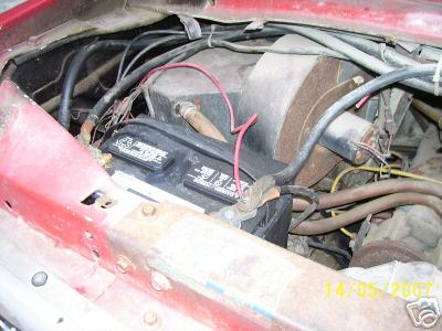 1978 Ford E250 - Close-up view of the engine bay, showing the battery, wiring, and various hoses.