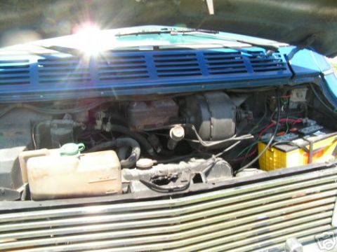 1978 Ford E250 - Engine bay of a van, showing various mechanical parts and the battery.