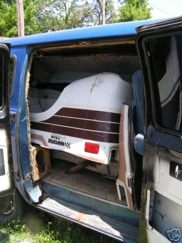 1978 Ford E250 - A camper shell is stored inside a blue van, showing significant wear and tear on the vehicle's interior.