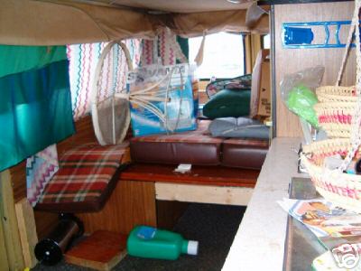 1978 Ford E250 - The interior of a camper van shows a lived-in space with various items stored around the seating area.