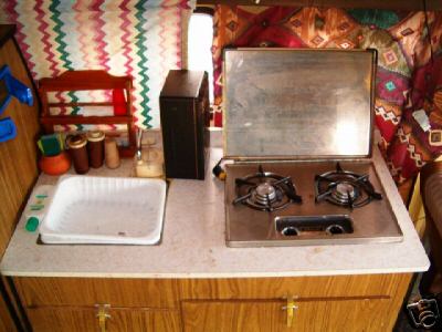 1978 Ford E250 - The interior of a camper features a sink and a propane stove with a metal lid.