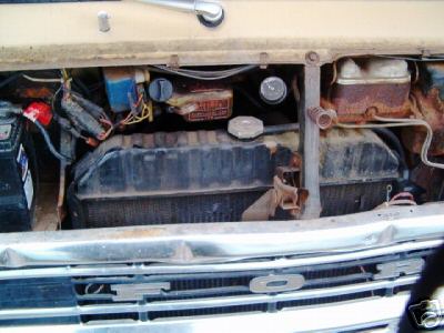 1978 Ford E250 - The engine bay of a vehicle, showing the radiator, battery, and various hoses and components.