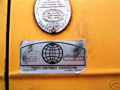 1978 Ford E250 - Close-up of a yellow vehicle's exterior, showing two metal plates with text and logos, including one from Travel Equipment Corporation.