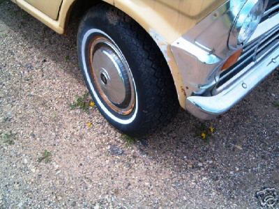 1978 Ford E250 - A close-up view of the front wheel and fender of a vintage van, showing its tire and chrome accents.