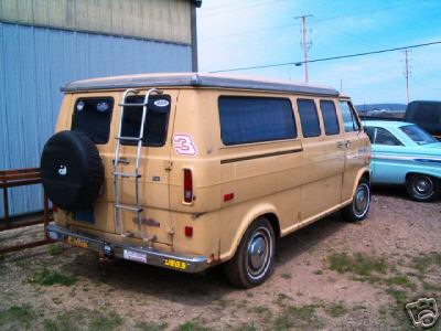 1978 Ford E250 - This van, likely a 1975 Ford Econoline, has a spare tire mounted on the rear and a ladder for roof access.