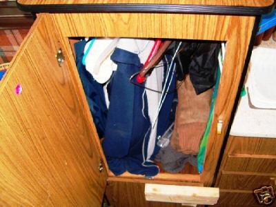 1978 Ford E250 - View inside a wooden cabinet filled with clothing items.
