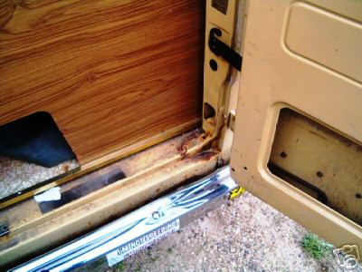 1978 Ford E250 - Close-up of the interior door frame and panel of a 1978 Ford E250, showing wood paneling and some rust.