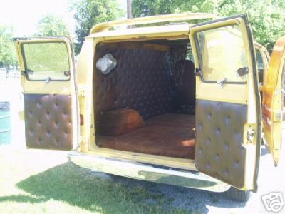 1978 Ford E250 - Rear view of a yellow van parked on grass with both barn doors swung open, revealing a custom cargo-area build with brown tufted button uph…