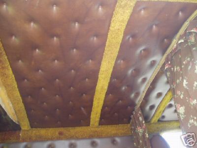 1978 Ford E250 - Looking up at a custom van's headliner finished in brown tufted button-studded vinyl panels separated by gold shag carpet strips, continuin…