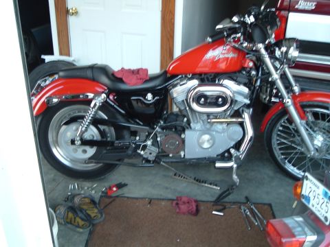 2002 Harley-Davidson Sportster Custom - A red Harley-Davidson motorcycle is parked in a garage, with tools scattered around its base.