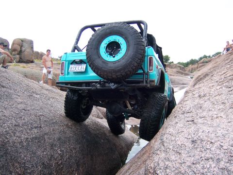 1979 Ford Bronco - 1979 Ford Bronco tackling a challenging off-road course with large rocks and water.