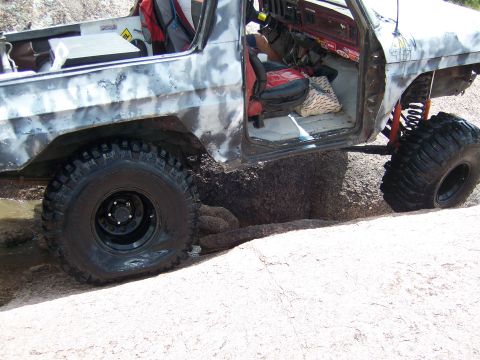 1979 Ford Bronco - This modified off-road vehicle appears to be stuck in a challenging terrain with one tire deflated.