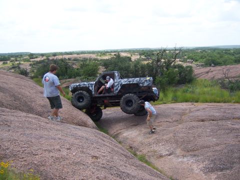 1979 Ford Bronco - Modified 1979 Ford Bronco tackling a challenging rocky trail with assistance from onlookers.