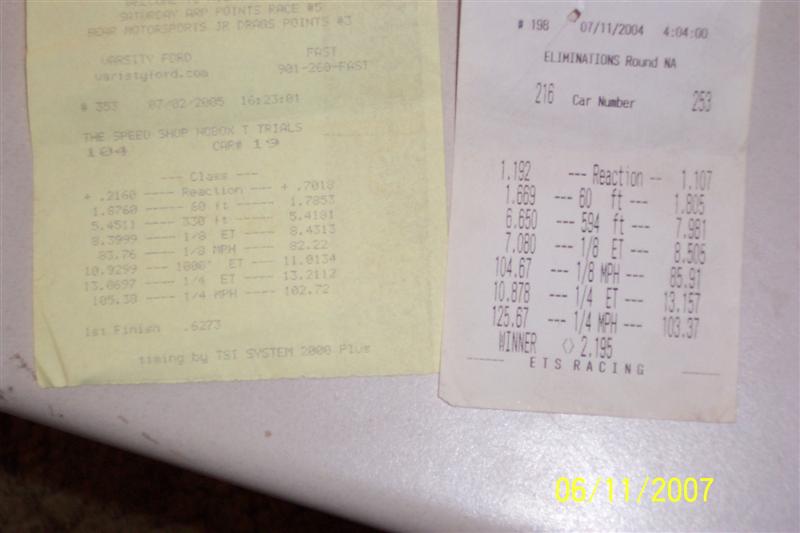 Two yellow and white paper time slips with drag racing data
