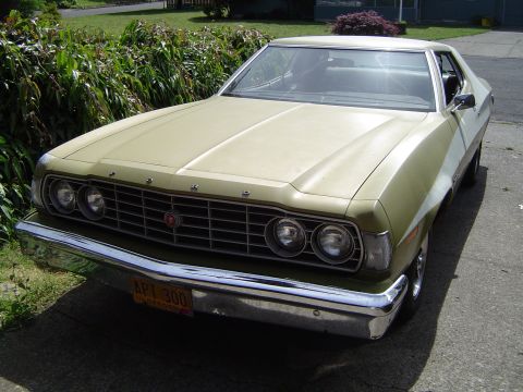 1973 Ford Torino - This 1973 Ford Torino features a distinctive grille and dual headlights, with a two-tone tan and white paint scheme.