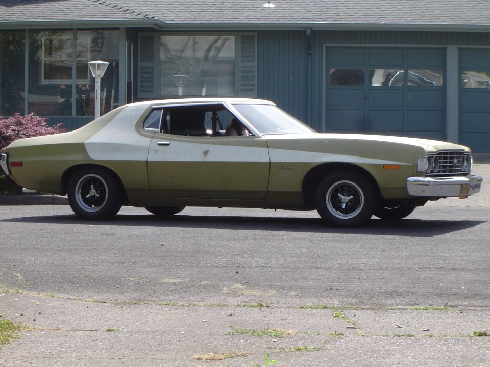 Olive-green Ford Torino two-door hardtop side view with white pillar stripe and black wheels