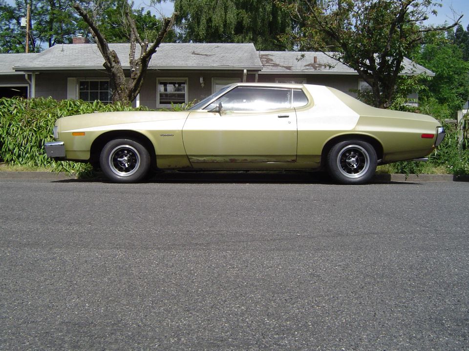 Faded gold 1970s Ford Torino two-door parked curbside in side profile