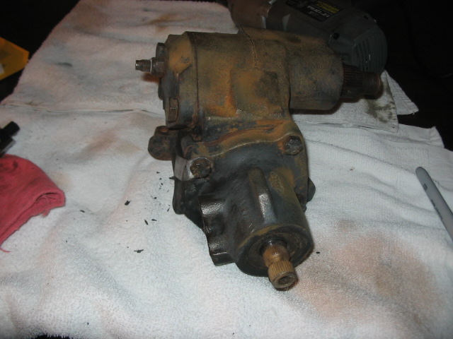 rusty power steering gearbox on a white towel with a red rag and a drill in the background