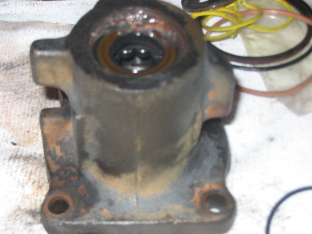 Close-up of a rusty hydroboost brake booster part with yellow and brown hoses in the background