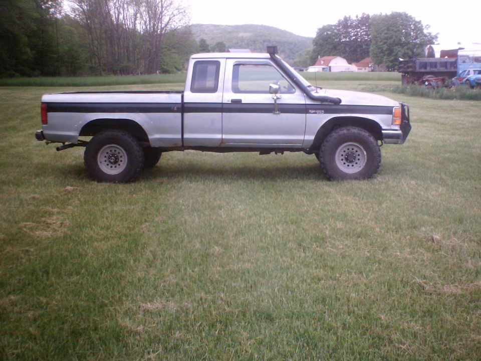 Silver Ford Ranger extended-cab pickup parked in a grassy field