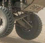 1990 Ford Bronco - cropped close-up of an off-road race truck's rear tire and coilover shock suspension over dirt.