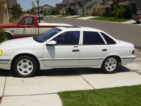 1995 Ford Taurus - Side profile of a white 1995 Ford Taurus sedan parked on a suburban driveway.