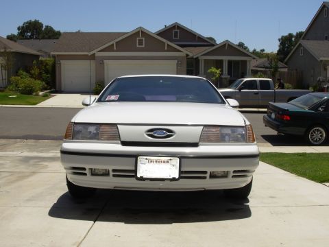 1995 Ford Taurus - White 1995 Ford Taurus front view, parked in a suburban driveway with other vehicles present.