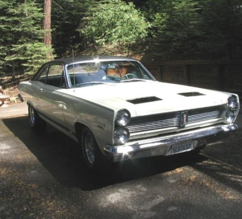 1973 Ford Ranchero - White 1966 Mercury Comet Cyclone coupe with a black roof and hood scoops is parked on a paved surface.