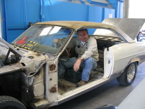 1973 Ford Ranchero - A man sits in the driver's seat of a 1966 Ford Ranchero undergoing restoration, showing its disassembled state.
