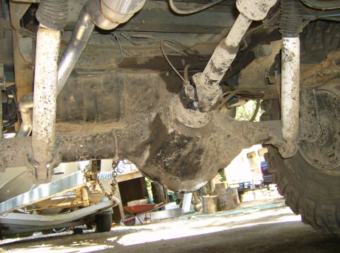 1986 Ford Bronco - This photo shows the undercarriage of a vehicle, focusing on the rear axle and suspension system, with a boat trailer in the background.
