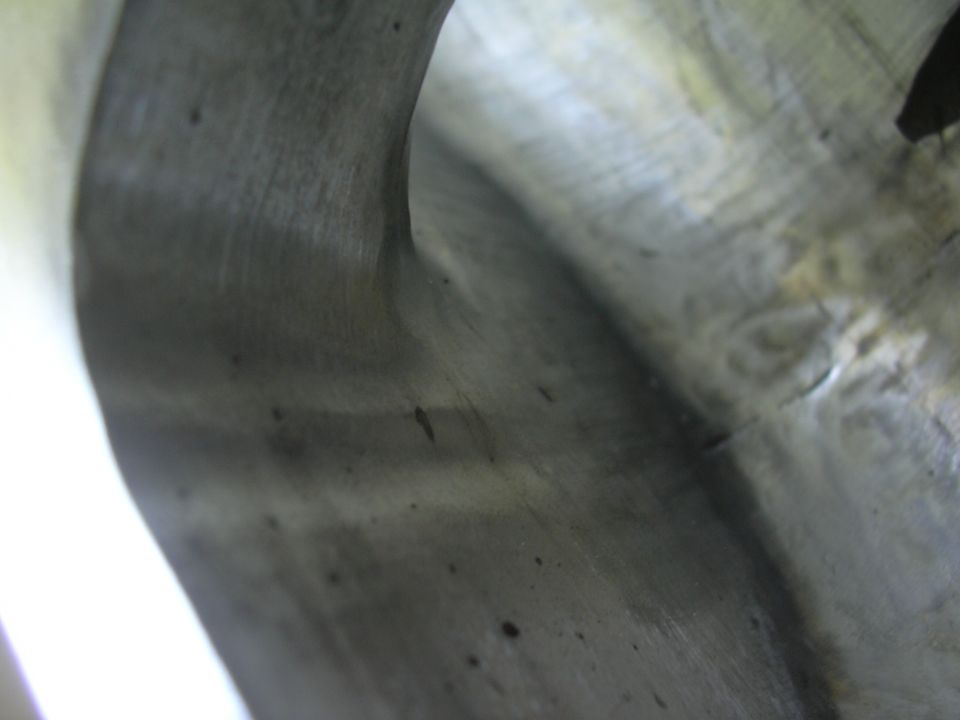 Close-up of an engine intake manifold with visible casting marks and some dark spots