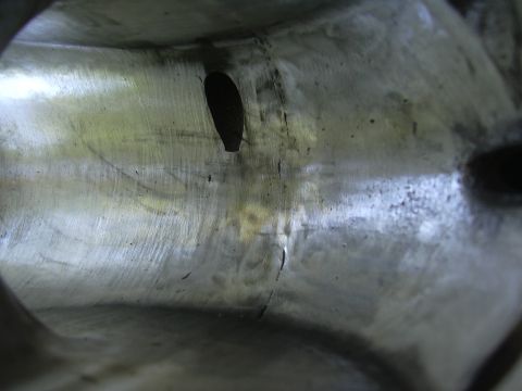 1996 Ford Crown Victoria - Close-up view inside a metal intake manifold, showing wear, a crack, and an oval-shaped opening.