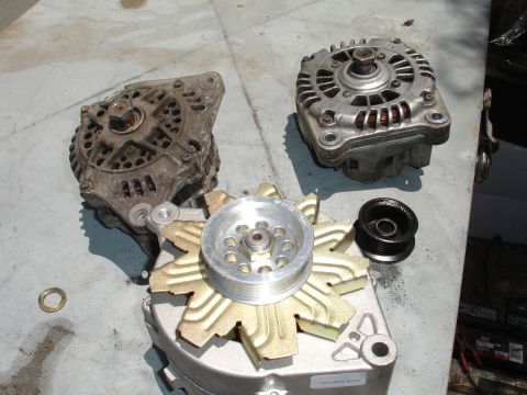 1993 Ford Taurus - Three alternators and a pulley are laid out on a table, suggesting a repair or upgrade.