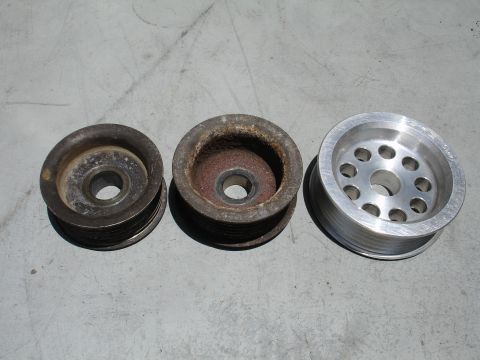 1993 Ford Taurus - Comparison of three automotive pulleys, showing two old units and one new aluminum replacement.