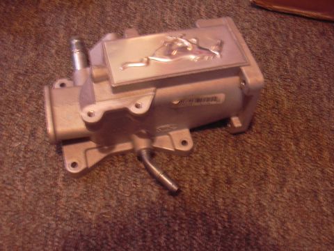 1996 Ford Crown Victoria - This aluminum plenum features an embossed Ford Mustang emblem and is shown resting on a carpeted surface.